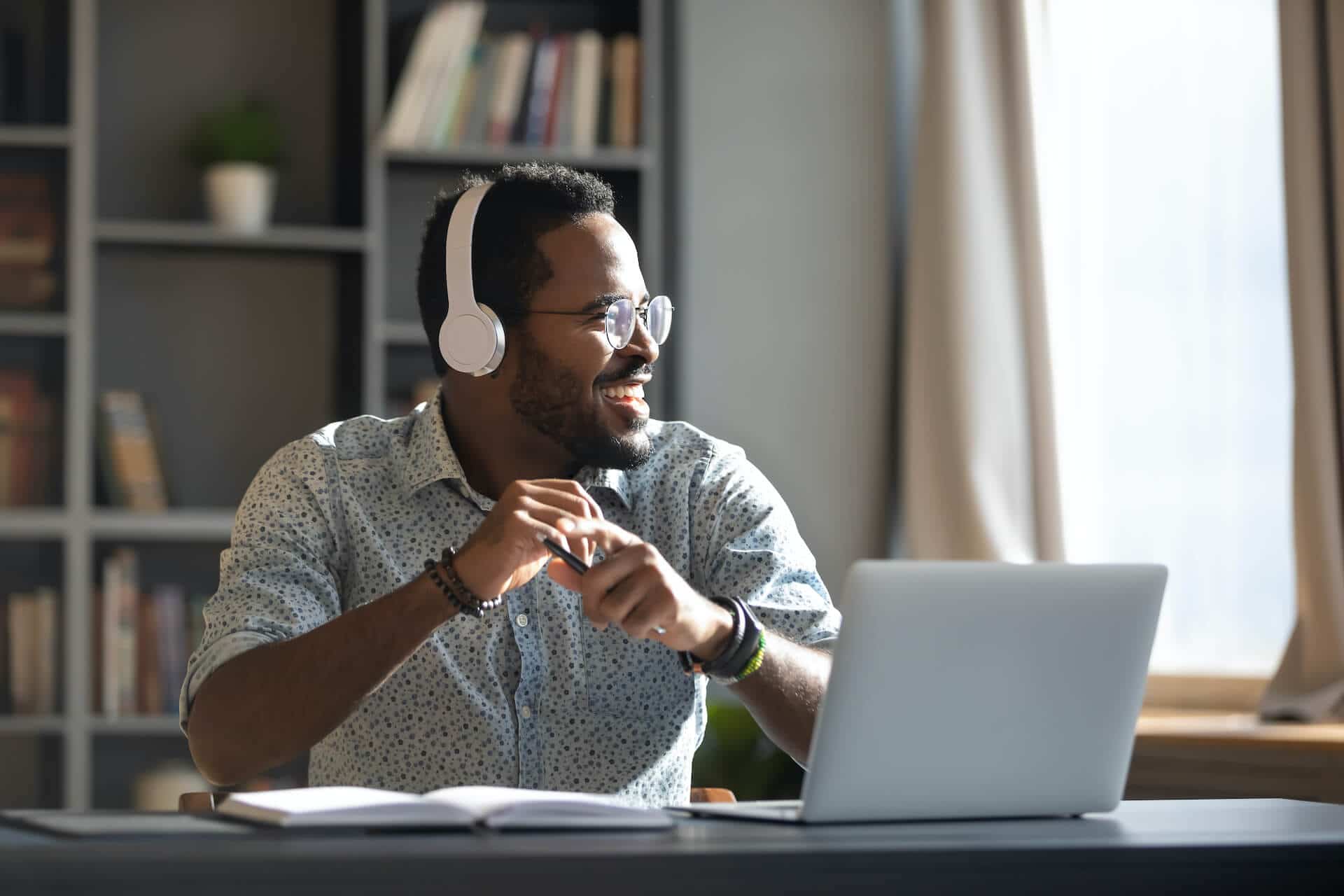 Smiling man with headphones working on laptop